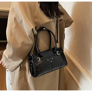 On-body view of black glossy leather crossbody bag with triangle logo and metal hardware