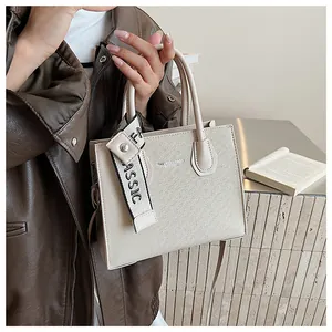 Detail of beige tote bag with woven texture, CLASSIC strap, and detachable shoulder strap