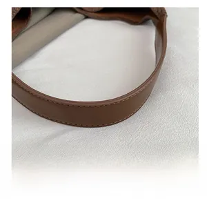 Detailed macro view of the brown leather shoulder strap with clean stitching and grey lining