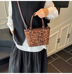 Detail of leopard print bucket bag with dual handles and adjustable strap worn by model