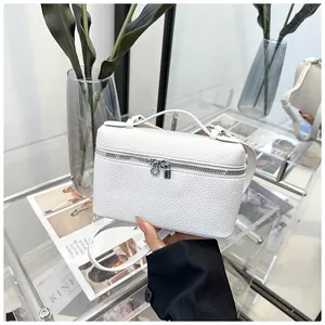Détail d'un sac à main en cuir blanc à motif litchi avec fermeture éclair en métal