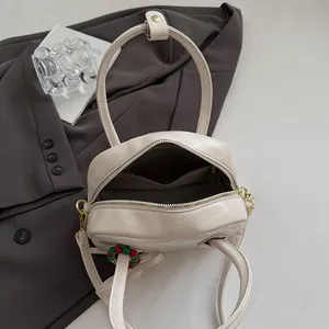 Sac polochon beige chic avec poignées et breloque perle dans un décor épuré