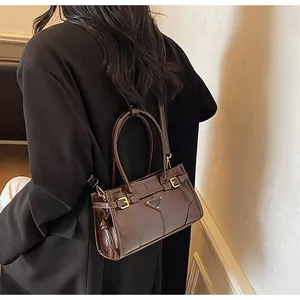 Detail view of dark coffee patent leather handbag with gold buckles and shoulder strap
