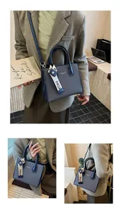 Detail of navy blue textured fabric and leather bag with silk scarf and shoulder strap