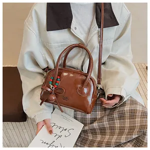 Gros plan du sac marron en cuir huilé avec logo embossé et pendentif à nœud chic