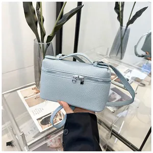 Gros plan du sac bandoulière en cuir bleu clair avec doubles fermetures éclair argentées