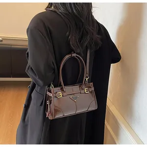 Detail view of brown patent leather handbag featuring triangle hardware and golden buckles