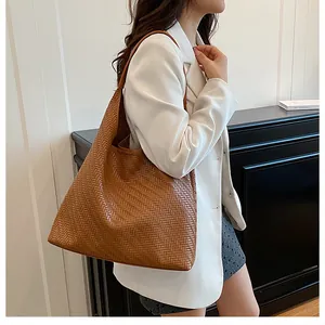 Brown woven leather bucket bag worn by model in a white blazer for casual commuting