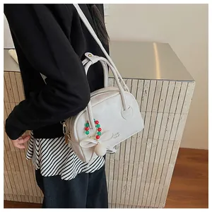 Détail d'un sac Boston blanc crème avec nœud décoratif et finition en similicuir texturé