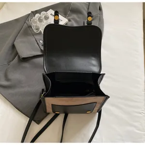 Detailed view of bicolor crossbody bag with internal zipper pocket and golden hardware