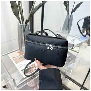 Détail de la texture en cuir noir à motif litchi et double fermeture éclair du sac à bandoulière