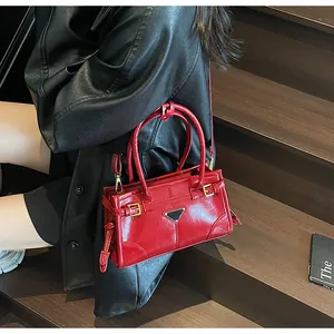 Macro view of red patent leather shoulder bag with triangle metal logo on dark stairs