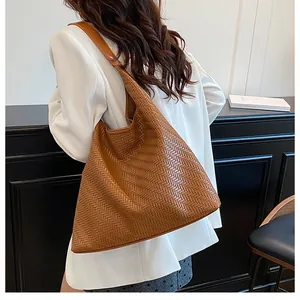 Detailed view of brown woven leather texture on a stylish commuter bucket shoulder bag