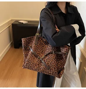 Dettaglio della borsa tote leopardata con cinturini in pelle marrone e fibbie in metallo
