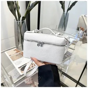 Détail du sac blanc à motif litchi avec fermetures éclair argentées et bandoulière