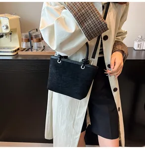 Close-up of black matte suede bucket bag with round handle and detachable shoulder strap
