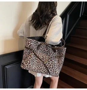 Dettaglio di una grande borsa tote leopardata con manici in pelle marrone indossata