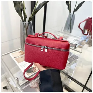 Détail d'un petit sac carré en cuir rouge litchi avec doubles fermetures éclair argentées