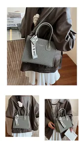 Detail of sage green square tote bag with leather texture and decorative printed ribbon