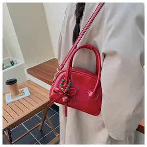 Sac à main rouge brillant avec bandoulière et pendentif décoratif en perles raffiné