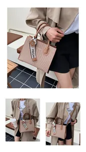 Detail of canvas tote bag showing brown leather handles and a decorative FASHI ribbon strap