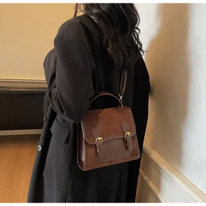 Brown vintage handbag worn by a model in a black blazer, showing crossbody style detail