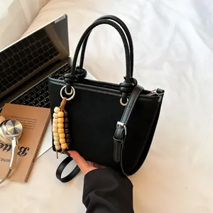 Minimalist black matte bucket bag with adjustable strap and wooden bead accessory
