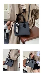 Detail of black woven texture crossbody bag with detachable strap and canvas pendant