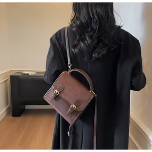 Detail of dark brown vintage suede leather crossbody bag worn with a long black coat