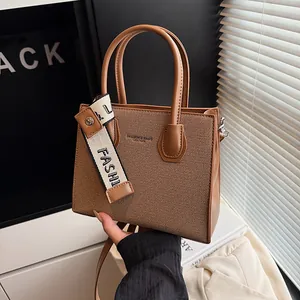 Fashionable canvas and leather crossbody bag with dual handles and fashion ribbon detail