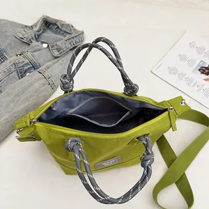 Fashionable green nylon tote bag with striped handles and crossbody strap in a casual layout