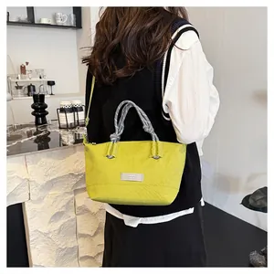 Detail of lime green shoulder bag with woven rope handle and fashion brand label