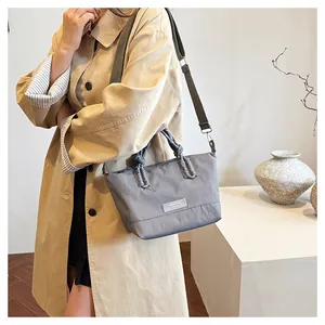 Close-up of gray nylon shoulder bag with braided handle and MOYLEE brand patch detail