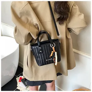 Details einer schwarzen geflochtenen Mini-Eimertasche mit Holzperlen und Schultergurt
