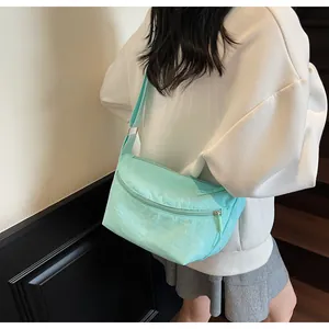 Detail of mint green nylon messenger bag with front zipper and wide fabric shoulder strap