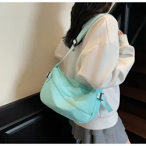 Detailed view of mint green nylon crossbody bag with adjustable strap and zip pockets