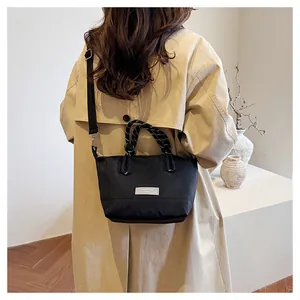 Detailed view of black nylon crossbody bag with woven handles and fashion label on a model