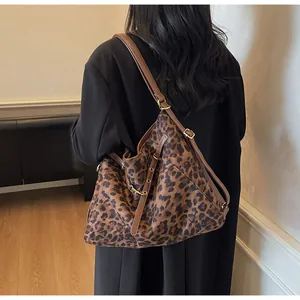 Detailed close-up of leopard print tote bag with brown leather strap and gold hardware
