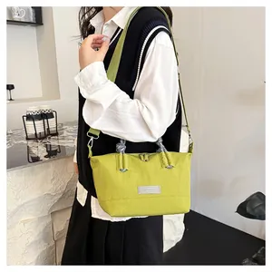 Detail of green canvas tote bag featuring woven rope handles and a fashion label