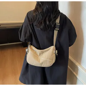 Detail of adjustable strap and buckle on a beige crescent-shaped nylon crossbody bag