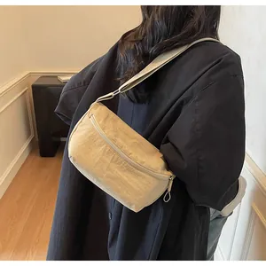 Rear view of a model wearing a beige nylon crossbody bag showing size and fit