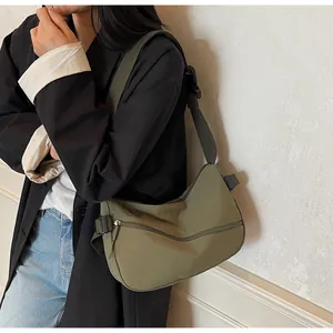 Olive green nylon crossbody bag with adjustable strap shown on a model in a black coat