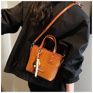 Detail der braunen Webstruktur-Eimertasche mit Holzperlenanhänger und Umhängeriemen