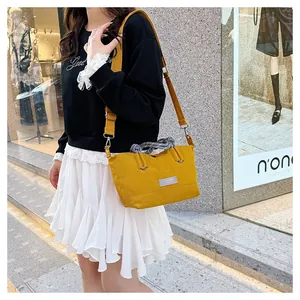 Model showcasing a bright yellow canvas crossbody bag with gray woven handle in street view