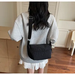 Detail of black nylon crossbody bag with adjustable wide strap and silver buckle closure