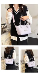 Detailed view of lavender shoulder bag with dual handles and adjustable strap in cafe setting