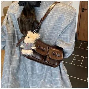Detail der dunkelbraunen Lackledertasche mit Schleifentaschen und Plüschbär-Anhänger