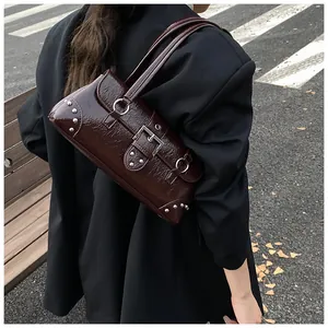 Detail of burgundy baguette bag with silver rivets and studs on urban street