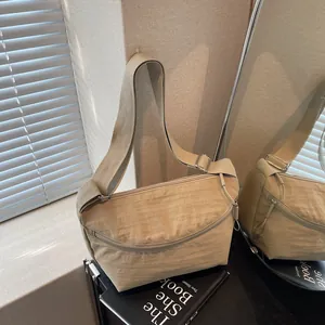 Minimalist beige nylon crossbody bag with adjustable strap and large capacity in a studio set