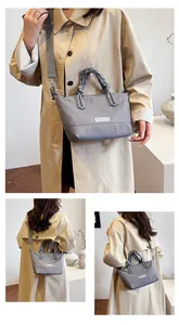 Detail of grey crossbody bag showing braided rope handles and fashion logo on nylon fabric